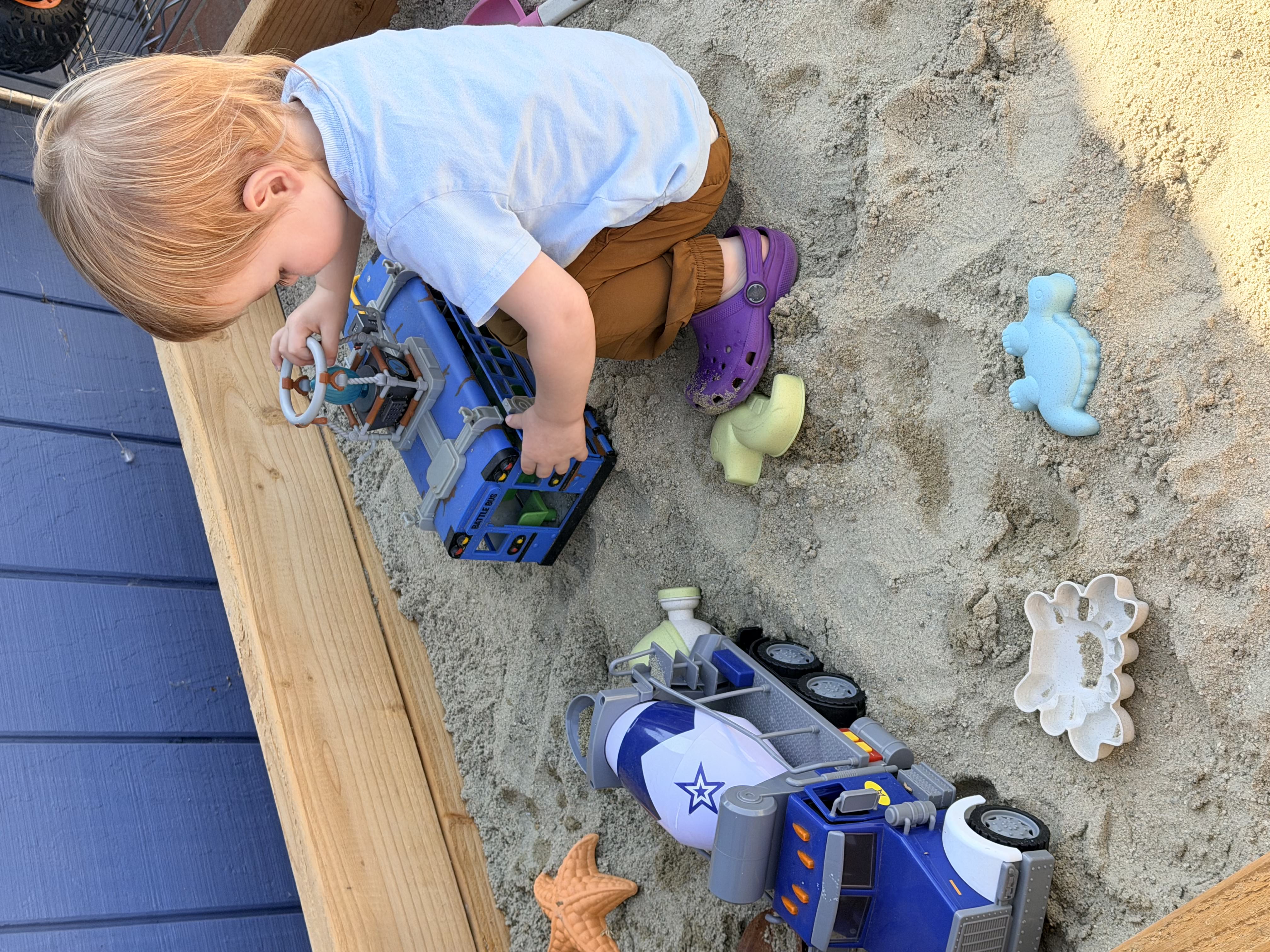Boy in sandbox with trucks